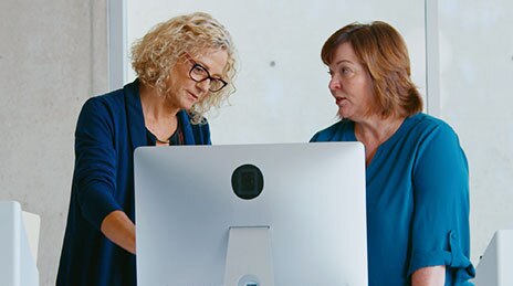 Two women conversing at computer.